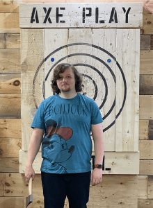 Axe Play Tommy holding an axe in front of the wooden target at our Hudson, NH venue